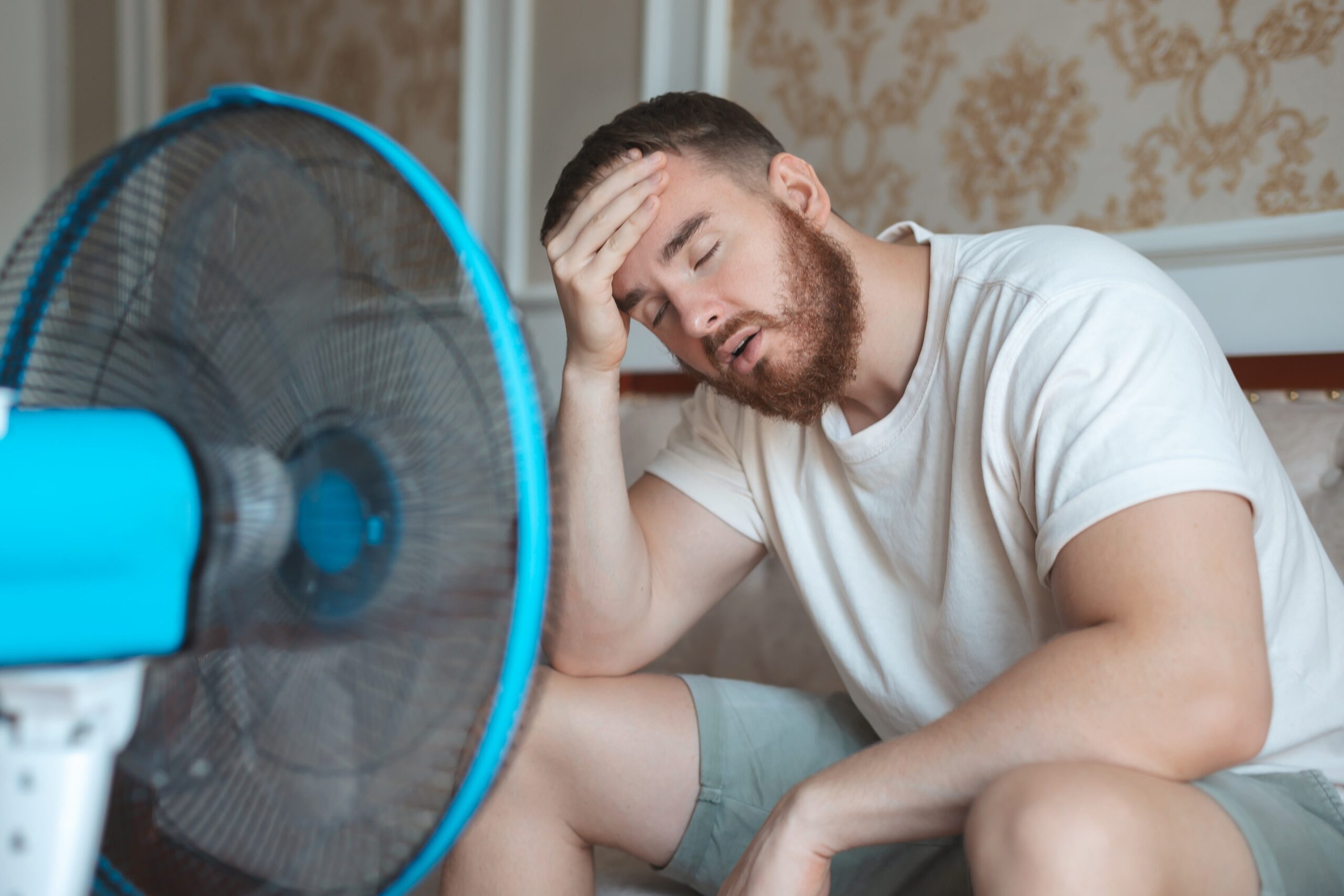 Man sat in front of a fan looking hot and weary